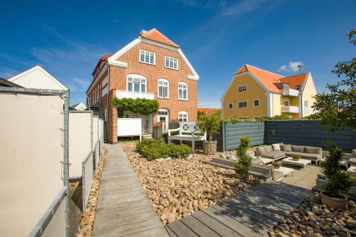 uma casa com um quintal com um passadiço de madeira em Plesners Badehotel em Skagen