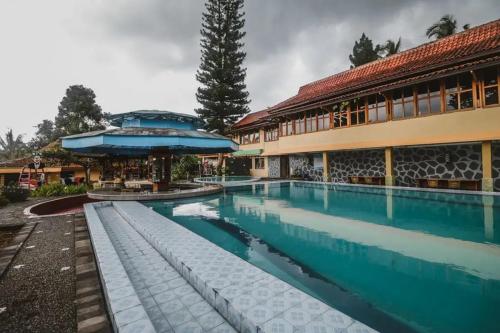 a swimming pool in front of a building at RedDoorz Plus at Neo Asri Hotel Megamendung Puncak Bogor in Bogor