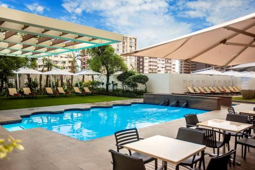 una imagen de una piscina en un hotel con mesas y sillas en Southern Sun Elangeni & Maharani en Durban