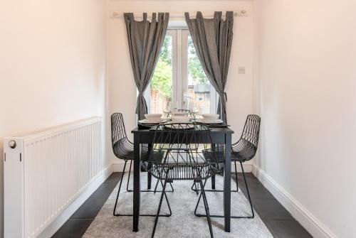 una mesa de comedor negra con sillas frente a una ventana en Lumley House - Delightful 2BR Terraced House near Birmingham en Walsall