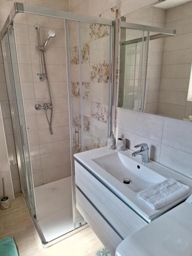 a white bathroom with a shower and a sink at ALPSKA ROŽA in Kranjska Gora