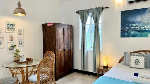 a bedroom with a table and a bed and a table and chairs at Nestwood - By The Beach Goa in Benaulim