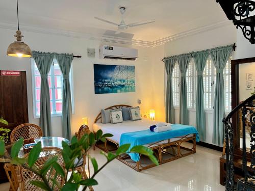 a bedroom with a bed in a room with windows at Nestwood - By The Beach Goa in Benaulim