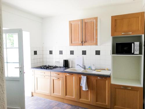 a kitchen with wooden cabinets and a microwave at L'ancien relai de poste de Magny-Cours in Magny-Cours