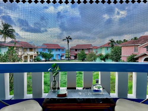 a table on a balcony with a view of houses at Nestwood - By The Beach Goa in Benaulim