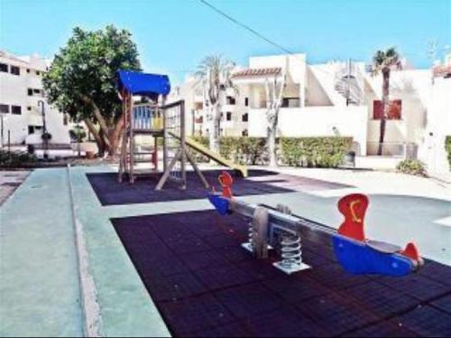 un parque infantil con tobogán y columpio en Acogedor apartamento en la Playa. Urbanización La Felicidad. Las Marinas en Dénia