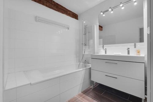 une salle de bain blanche avec une baignoire et un lavabo dans l'établissement Le Havre des Tanneurs - Appt dans l'hyper-centre de Toulouse, à Toulouse