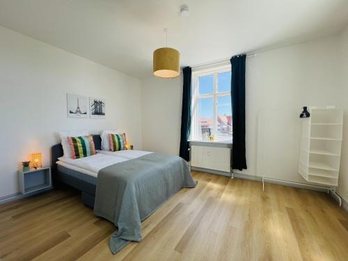 een slaapkamer met een bed en een groot raam bij aday - Green Light Apartment Suite in the center of Hjorring in Hjørring