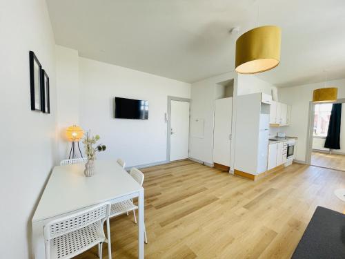 Il dispose d'une cuisine et d'un salon avec une table et des chaises blanches. dans l'établissement aday - Green Light Apartment Suite in the center of Hjorring, à Hjørring