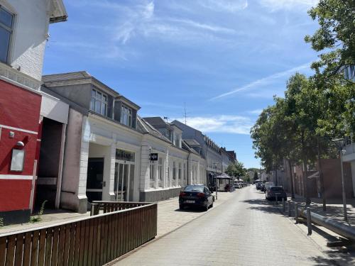 a street with houses and cars parked on the street at aday - Green Light Apartment Suite in the center of Hjorring in Hjørring