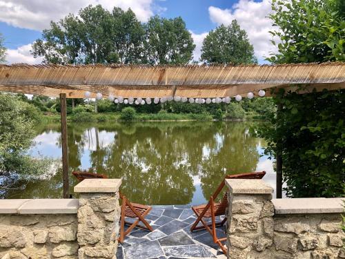 a patio with chairs and a pond with a straw umbrella at Chalet La Bohème in Prouilly