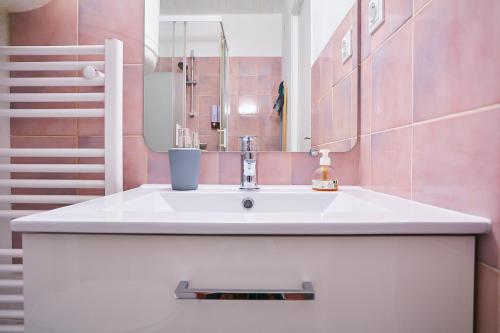 a bathroom with a white sink and pink tiles at L'appartement in Pontarlier