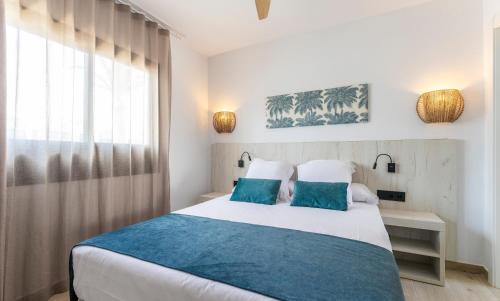 Un dormitorio con una cama con almohadas azules y una ventana en Bakour Lanzarote Splash en Puerto del Carmen