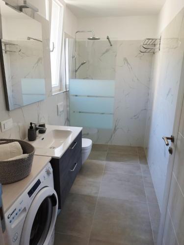 a bathroom with a sink and a washing machine at M&D appartments in Komiža