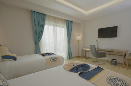 a hotel room with two beds and a desk at Stay Easy Plus Hotel in Addis Ababa