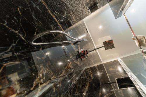 a shower in a bathroom with a black tiled wall at Suites Matteotti 57 in Civitavecchia