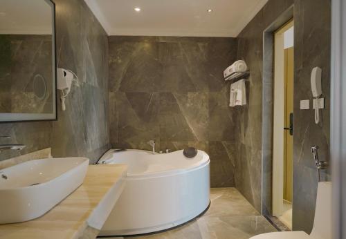 La salle de bains est pourvue d'une baignoire blanche et d'un lavabo. dans l'établissement Stay Easy Plus Hotel, à Addis-Abeba