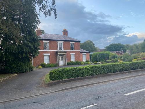 a red brick house with a road in front of it at Creamore Grove Wem Shrewsbury in Wem