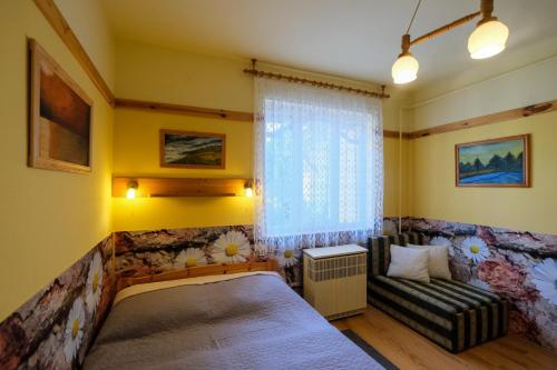 a bedroom with a bed and a couch and a window at 4 Évszak Apartman in Gyula