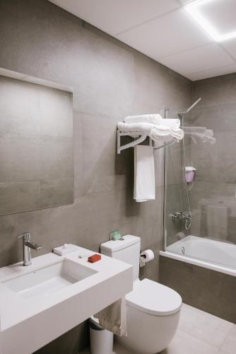 a bathroom with a toilet and a sink and a tub at Hotel Melilla Centro in Melilla