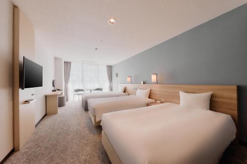 a hotel room with two beds and a flat screen tv at Kyoto Tower Hotel in Kyoto