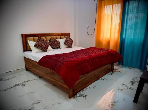 a bedroom with a bed with a red blanket and pillows at RAMALAYAM in Ayodhya