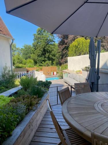 a patio with a table and chairs and an umbrella at Maison de l'Aumance in Meaulne