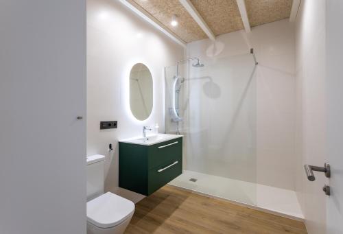 a bathroom with a shower and a toilet and a sink at Alma Marina Apartamentos in Somo