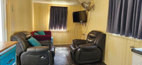 a living room with two chairs and a tv at Golden Mt Rest off Pepperina Lane in Mount Morgan