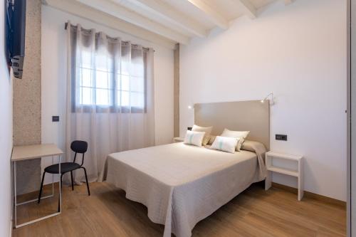 a white bedroom with a bed and a window at Alma Marina Apartamentos in Somo