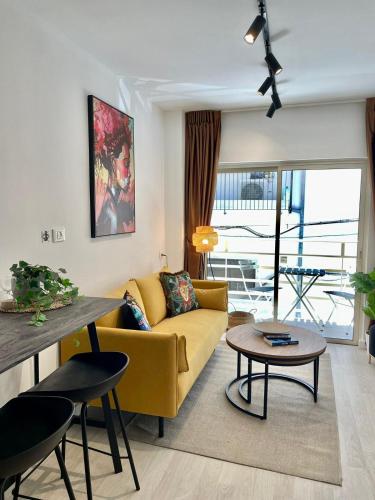 Haneemanim Apartments في حيفا: غرفة معيشة مع أريكة صفراء وطاولة