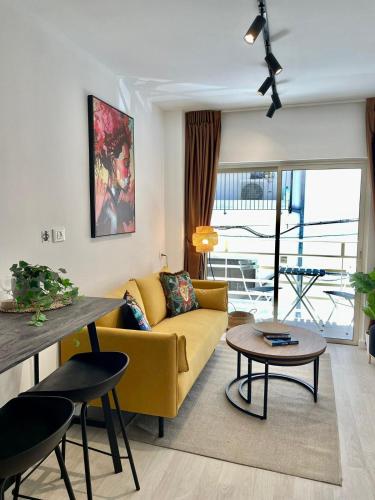 Una sala de estar con un sofá amarillo y una mesa. en Haneemanim Apartments, en Haifa