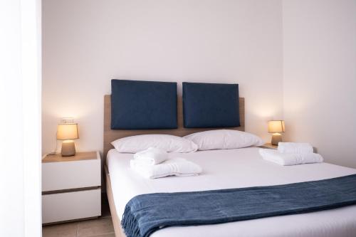 a bedroom with a large white bed with two lamps at Nautika Suites in Alghero