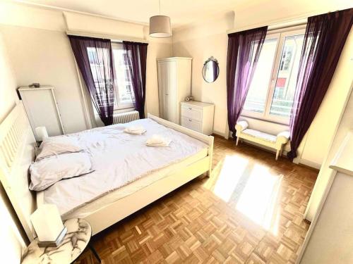 een slaapkamer met een groot wit bed en 2 ramen bij CH Apartment Lausanne Gare in Lausanne