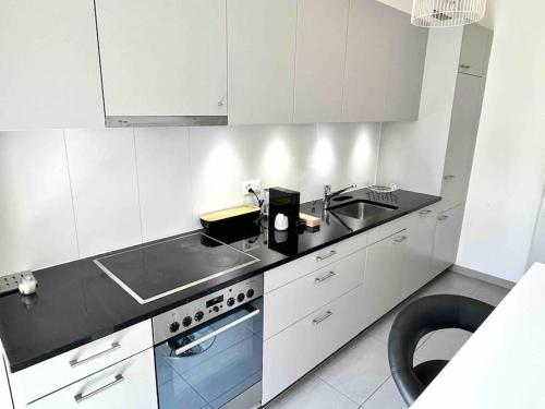 a white kitchen with a sink and a stove at CH Apartment Lausanne Gare in Lausanne