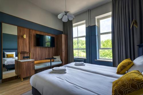 um quarto de hotel com uma cama e uma televisão e janelas em SEPHS Hotel Sittard em Sittard