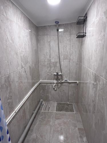 een betegelde badkamer met een douche met een slang bij Bayraktar apart in Pelitli