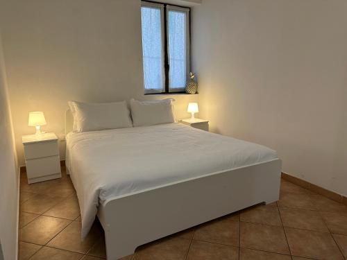 a bedroom with a large white bed with two lamps at Novi apartment in Novi Ligure