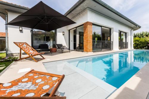 - une piscine avec une chaise et un parasol à côté d'une maison dans l'établissement VILLA DU GOLF - Keyweek- Villa Biarritz with swimming pool, à Biarritz