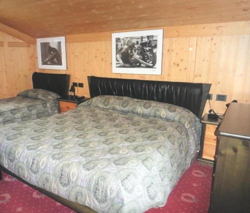 a bedroom with a bed and two pictures on the wall at Chalet Rosj in Moena