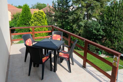 a black table and four chairs on a balcony at 4 Évszak Apartman in Gyula