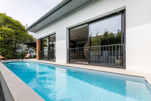 - une piscine en face d'une maison avec fenêtres dans l'établissement VILLA DU GOLF - Keyweek- Villa Biarritz with swimming pool, à Biarritz