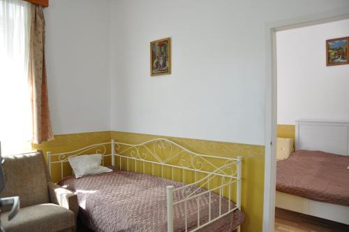 a bedroom with a bed and a chair and a mirror at Gloriett Panzió in Fertőboz