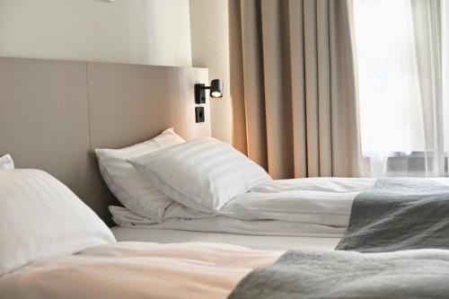 a bedroom with two beds with white sheets and a window at Hotel Local 101 in Reykjavík