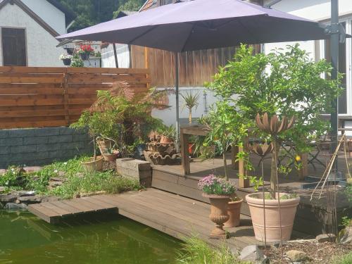 eine Terrasse mit einem Sonnenschirm und einem Teich mit Topfpflanzen in der Unterkunft Ferienwohnung Katrin in Mettlach