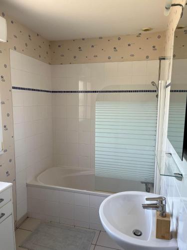 une salle de bain blanche avec une baignoire et un lavabo dans l'établissement Villa baba, à Cholet