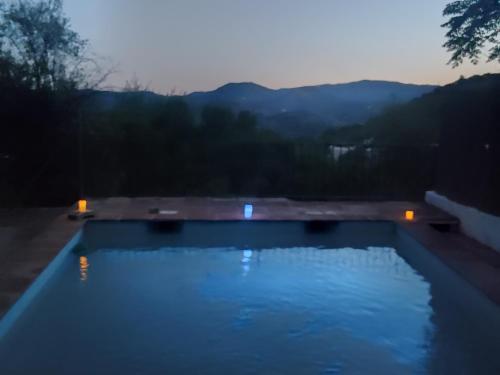 ein Schwimmbad in der Nacht mit Bergen im Hintergrund in der Unterkunft Casa rural con encanto in Colmenar
