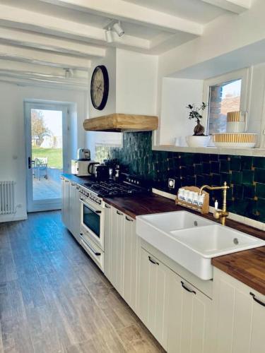 une cuisine avec un évier et une horloge murale dans l'établissement Maison campagne piscine 1hParis 25m Fontainebleau, à Préaux