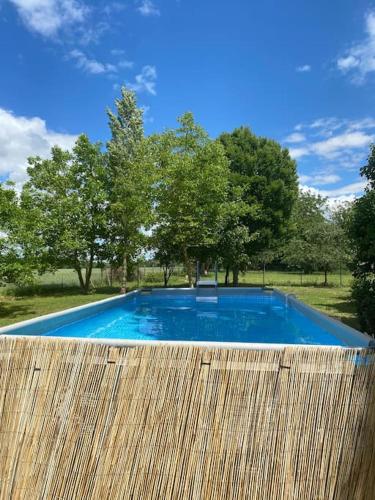 une piscine bleue à côté d'une clôture en bois dans l'établissement Maison campagne piscine 1hParis 25m Fontainebleau, à Préaux