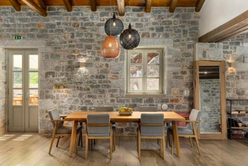 a dining room with a stone wall and a wooden table and chairs at Trapela Limeni Luxury Suites in Limeni